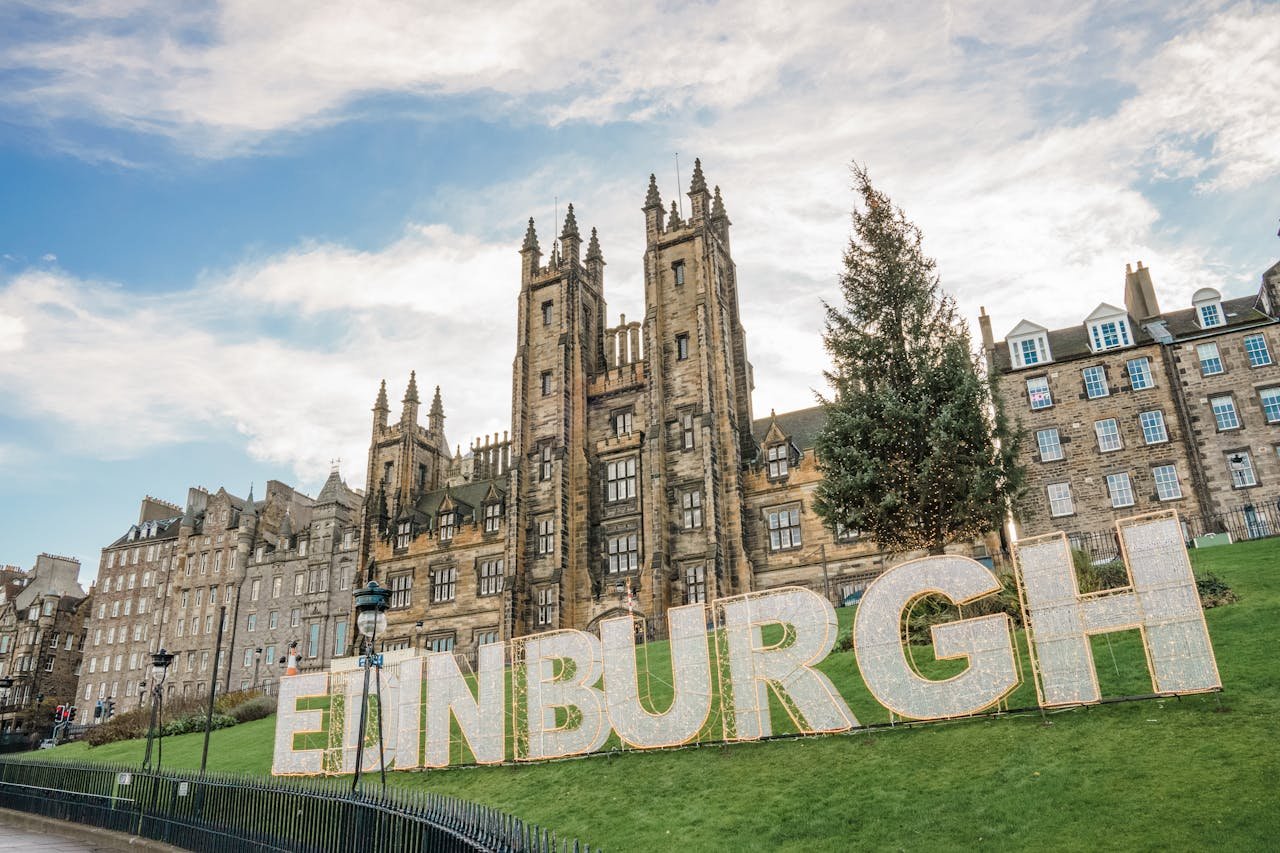 Offerings Iconic Edinburgh architecture with illuminated sign and scenic backdrop.