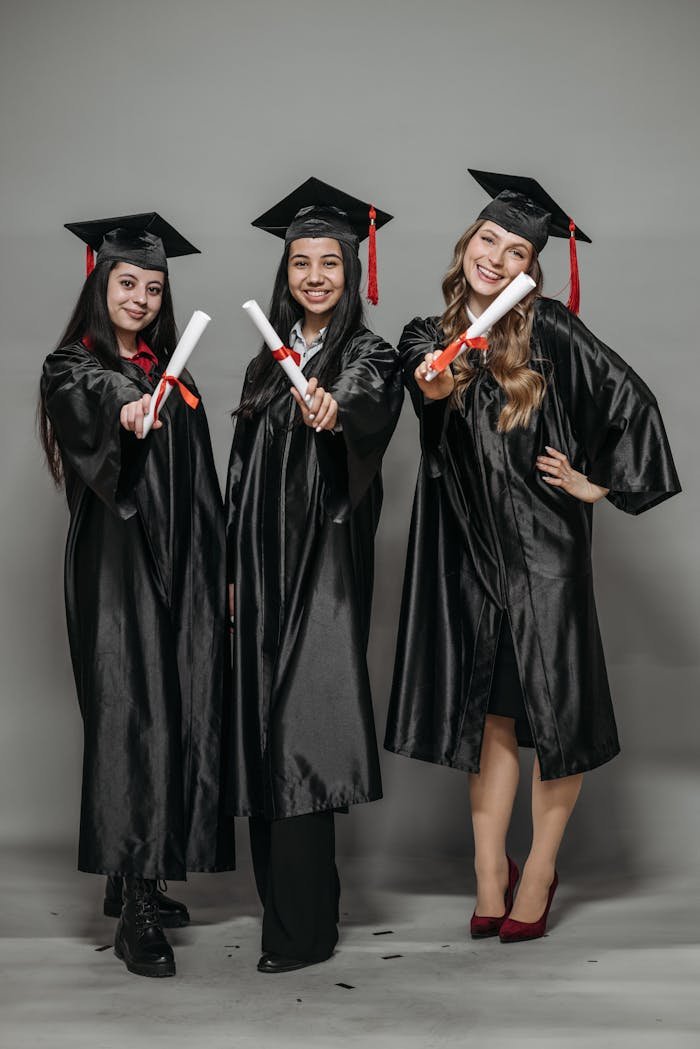 Crafting Captivating Headlines: Your awesome post title goes here Three women in graduation gowns celebrating with diplomas, smiling proudly.